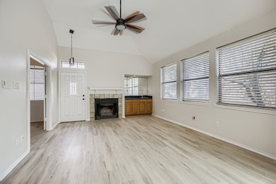 Unfurnished living room featuring light wood-type flooring, a ceiling fan, a tiled fireplace, and high vaulted ceiling