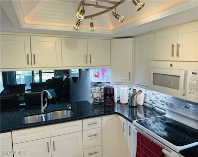 Kitchen featuring white appliances, a sink, white
