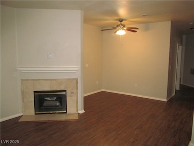 Unfurnished living room featuring a fireplace, dark wood-style flooring, and ceiling fan