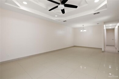 Spare room with light tile patterned floors, baseboards, visible vents, a raised ceiling, and ceiling fan with notable chandelier