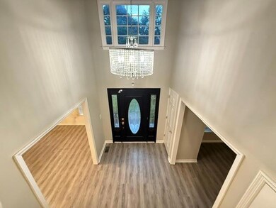 Foyer featuring a towering ceiling, wood finished floors, and a chandelier