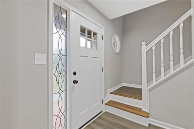 Entrance foyer with stairs, baseboards, and wood f