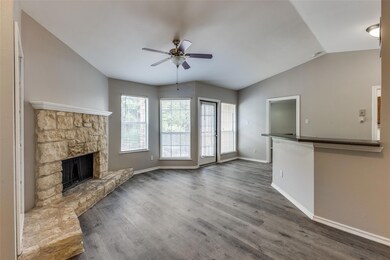 Unfurnished living room with ceiling fan, dark wood-style flooring, lofted ceiling, and a fireplace