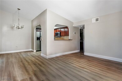 Unfurnished living room with lofted ceiling, arched walkways, a chandelier, and wood finished floors