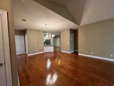 Unfurnished living room with a chandelier, baseboards, and dark wood finished floors