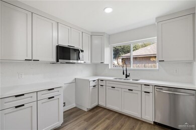 Kitchen featuring sink, appliances with stainless steel finishes, white cabinetry, backsplash, and dark hardwood / wood-style flooring
