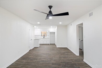 Unfurnished living room featuring ceiling fan and sink