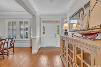 Foyer with light wood-style floors, healthy amount of natural light, crown molding, and a wainscoted wall