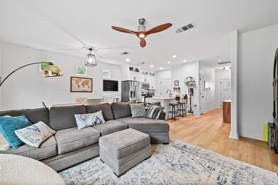 Living area featuring a ceiling fan, light wood-t