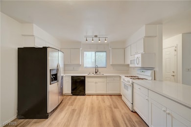 Kitchen with stainless steel refrigerator with ice dispenser, white range with gas cooktop, light wood finished floors, white cabinets, and dishwasher