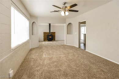 Unfurnished living room featuring a wood stove, ca