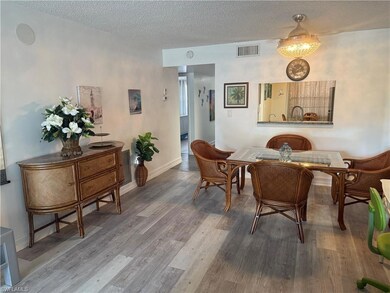Dining space with wood finished floors, a textured ceiling, and baseboards