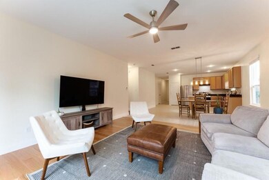 Living room with ceiling fan and light wood-type f