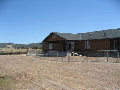 Back of home is fenced with back porch and a garde