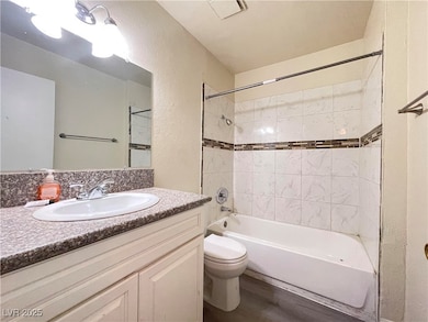 Full bath featuring a textured wall, vanity, batht