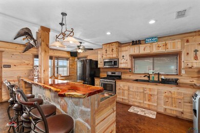 Kitchen featuring wood counters, light brown cabinetry, decorative light fixtures, appliances with stainless steel finishes, and wooden walls