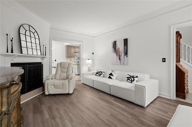 Living room featuring a fireplace, crown molding, and wood finished floors