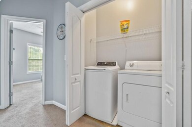 Laundry room featuring light carpet and washer and