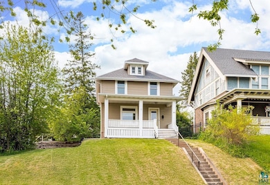 American foursquare style home with a porch and a front lawn