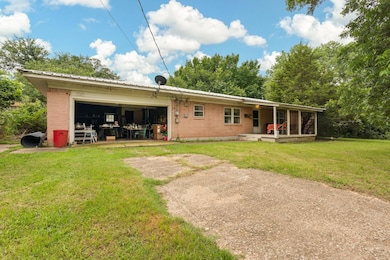 Rear view of house featuring a garage and a lawn
