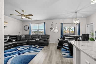 Living room with a chandelier, light wood finished floors, and a ceiling fan