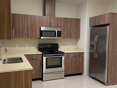 Kitchen featuring stainless steel appliances, a sink, light countertops, and light tile patterned flooring
