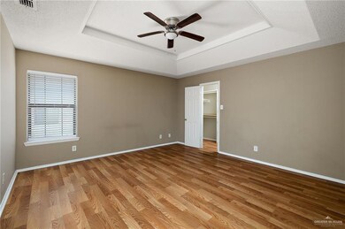 Unfurnished room featuring hardwood / wood-style flooring, ceiling fan, a textured ceiling, and a tray ceiling