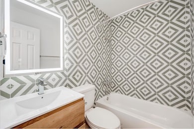 Bathroom with tile walls, vanity, and shower / bath combination
