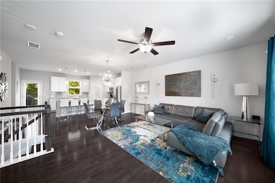 Living area with ceiling fan, dark wood-style floors, recessed lighting, and a chandelier