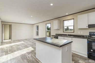 Kitchen with electric range, dark countertops, light wood-type flooring, a kitchen island, and recessed lighting