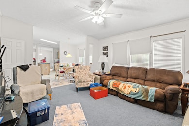 Carpeted living room featuring a textured ceiling and ceiling fan