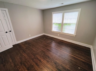 Empty room with dark wood-style floors, baseboards, and a textured ceiling