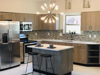 Kitchen featuring a center island, stainless steel appliances, a sink, and light countertops
