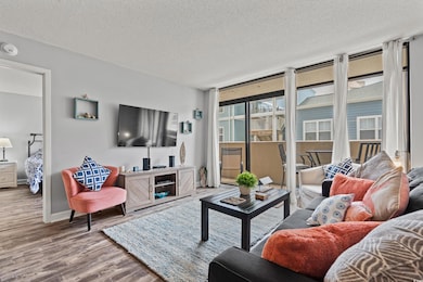 Living room with a textured ceiling, a wall of win
