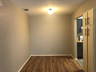 Unfurnished dining area featuring a textured ceiling and dark wood-style floors