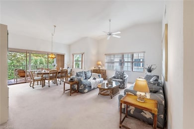 Carpeted living room with healthy amount of natural light, high vaulted ceiling, and a ceiling fan