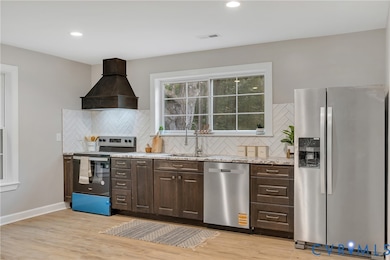 Kitchen featuring appliances with stainless steel finishes, dark brown cabinets, premium range hood, backsplash, and recessed lighting