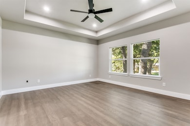 Spare room with a raised ceiling, wood finished floors, ceiling fan, and recessed lighting
