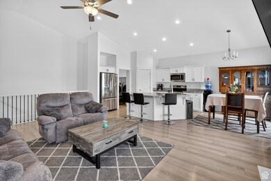 Living area with light wood-type flooring, a chandelier, a ceiling fan, recessed lighting, and high vaulted ceiling