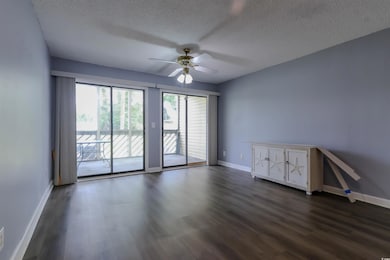 Empty room featuring ceiling fan, a textured ceiling, baseboards, and dark wood-type flooring