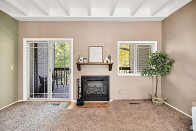 Carpeted living area featuring beamed ceiling, a fireplace, and a textured wall
