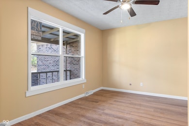 spare room with a textured ceiling, wood finished floors, baseboards, and visible vents