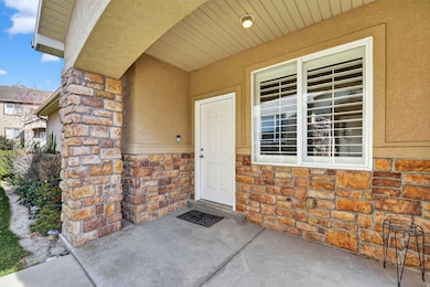 View of exterior entry featuring stone siding, a patio, and stucco siding