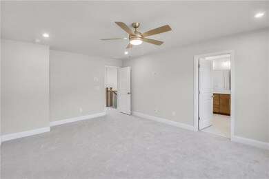 Unfurnished bedroom featuring recessed lighting, light colored carpet, ceiling fan, and ensuite bath