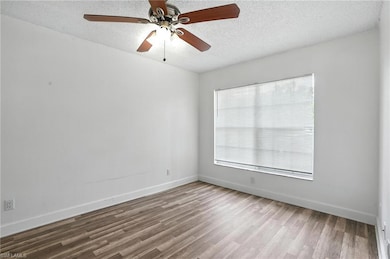 Empty room with wood finished floors, a textured ceiling, healthy amount of natural light, and ceiling fan