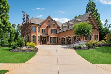 Georgian-style home with brick siding, driveway, a front lawn, and a garage