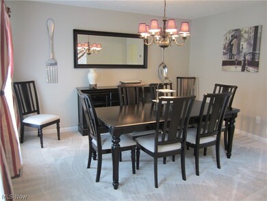 Carpeted dining area featuring an inviting chandelier