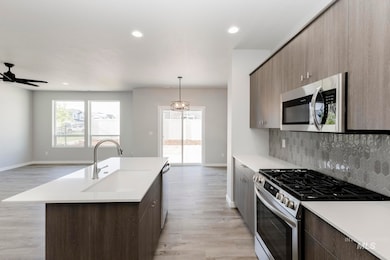 Kitchen featuring appliances with stainless steel finishes, pendant lighting, light wood finished floors, recessed lighting, and decorative backsplash