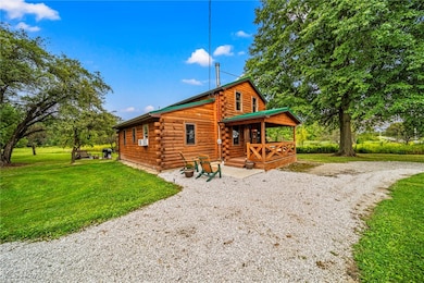 View of front of property with log siding, a front yard, a porch, and gravel driveway