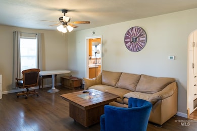 Living area featuring dark wood-style floors, ceiling fan, and arched walkways